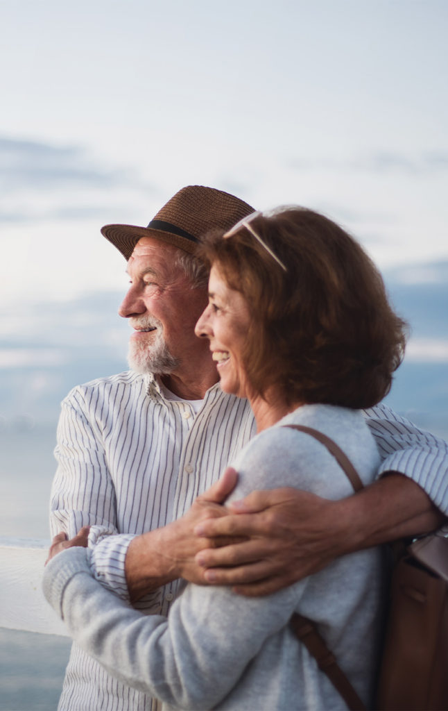senior couple standing on deck with lake behind them annuities for retirement
